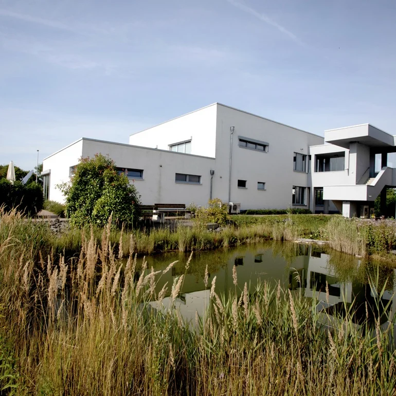 Das große weiße EMS-Gebäude in Brumby, tagsüber, von der anderen Seite ihres angelegten Teiches, aufgenommen.