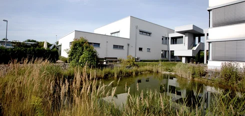 Das große weiße EMS-Gebäude in Brumby, tagsüber, von der anderen Seite ihres angelegten Teiches, aufgenommen.