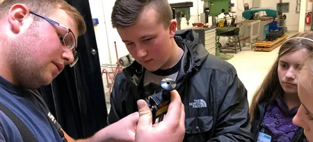 Eine Fachkraft erklärt mehreren Jugendlichen ein Gerät